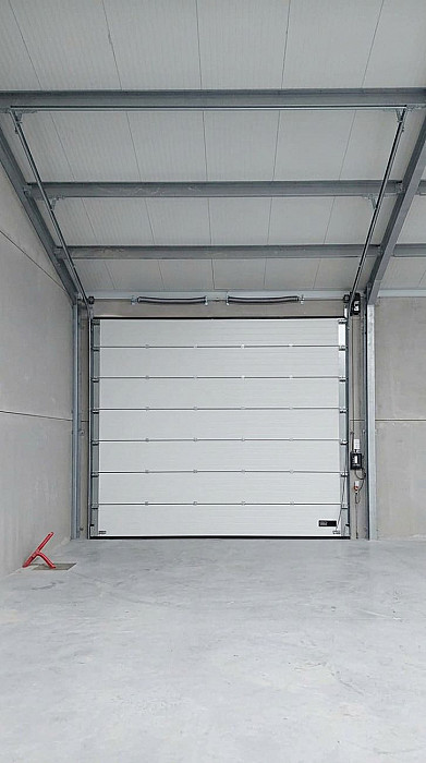 Porte sectionnelle industrielle blanche vue de l'intérieur d'un hall