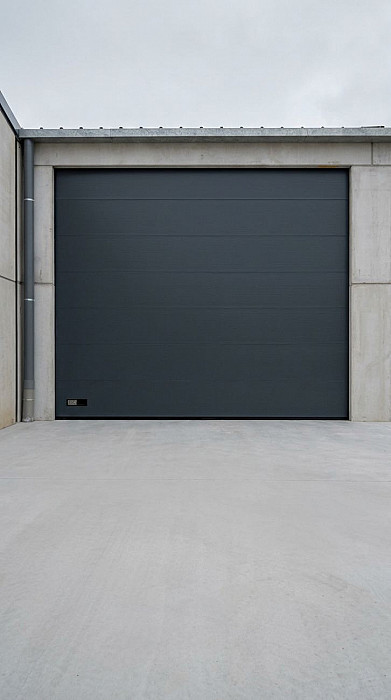 Porte sectionnelle industrielle anthracite vue depuis l'extérieur d'un hall