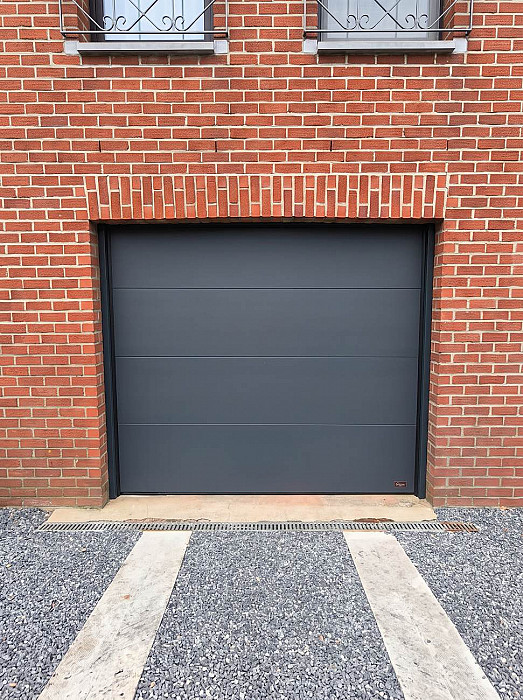 Porte sectionnelle anthracite installée sur une maison en brique rouge