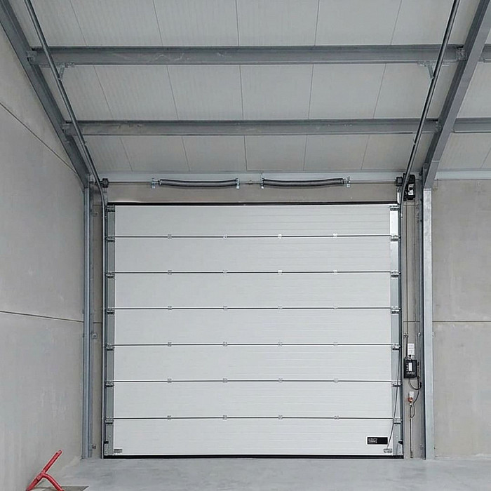 Porte sectionnelle industrielle vue de l interieur d un hall, intervention de depannage