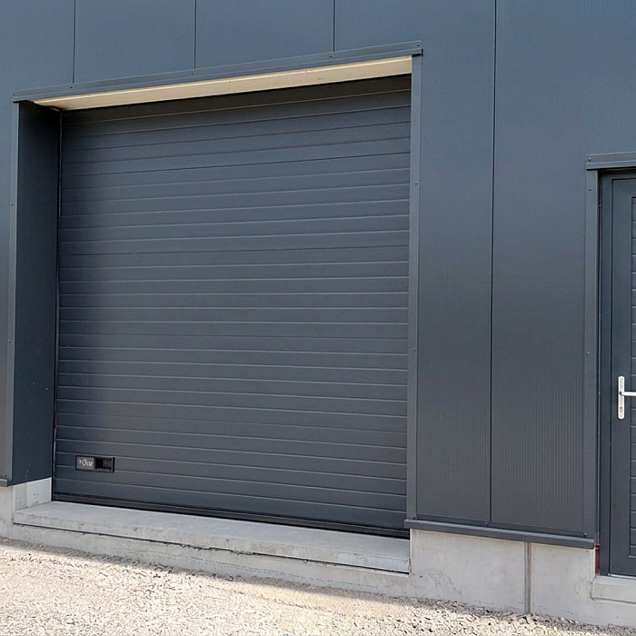 Porte sectionnelle industrielle et portillon de service sur un batiment logistique