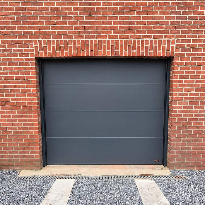 Porte sectionnelle anthracite posee sur une facade en brique par MFD Concept